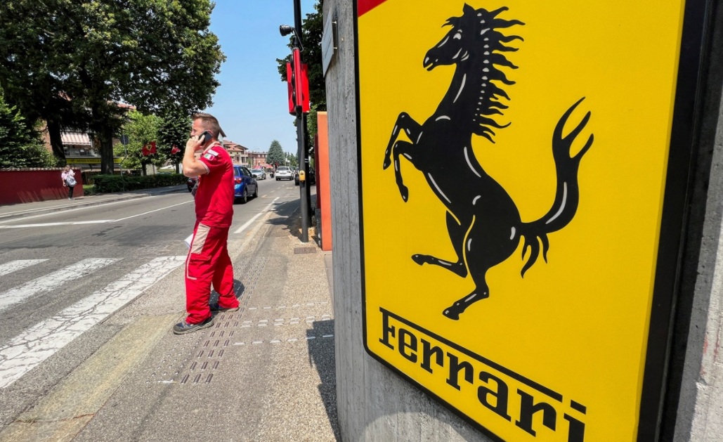 Um funcionário da Ferrari fala ao telefone ao lado do logotipo da Ferrari do lado de fora da fábrica, em Maranello, Itália, 15 de junho de 2022